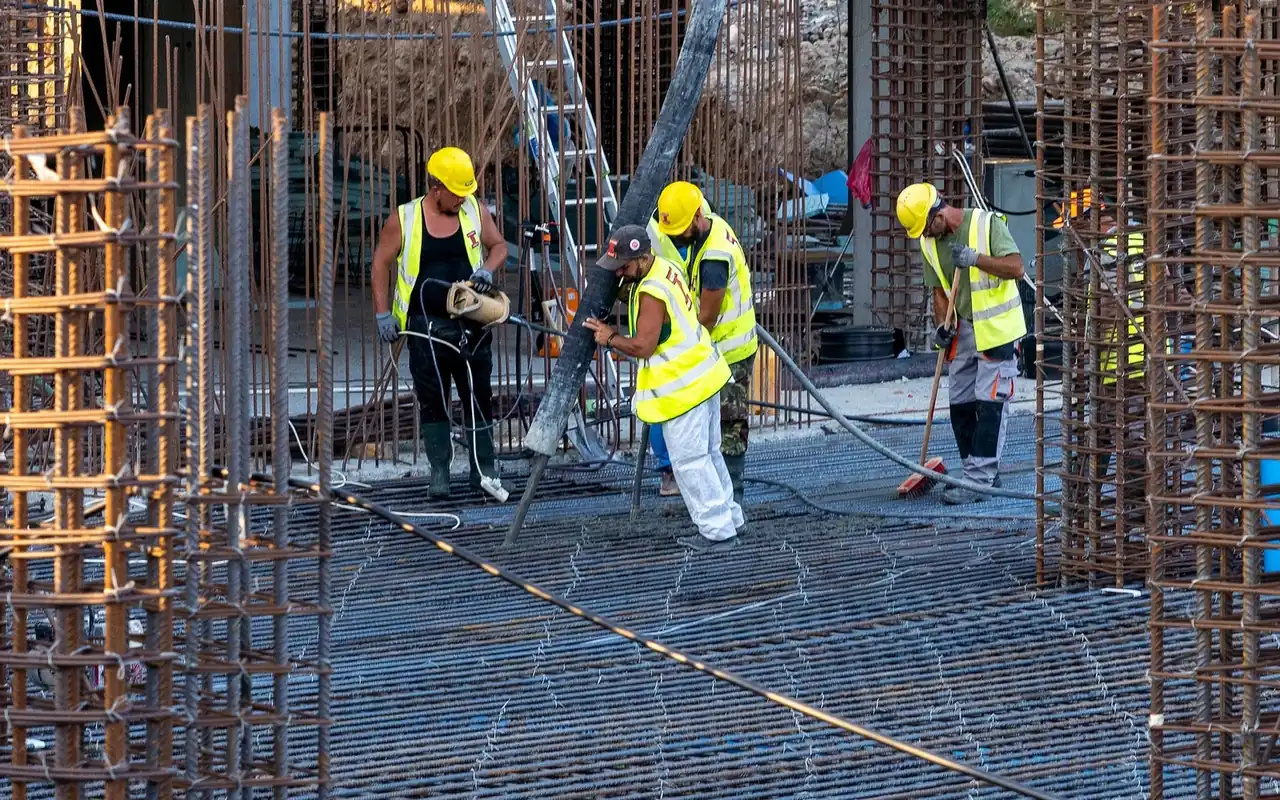 Crew in high-visibility vests placing concrete over a rebar deck