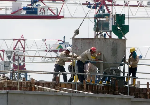 Crew guiding a crane-lifted concrete bucket on a tower deck