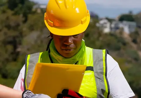 Engineer in PPE checking a plan on a tablet
