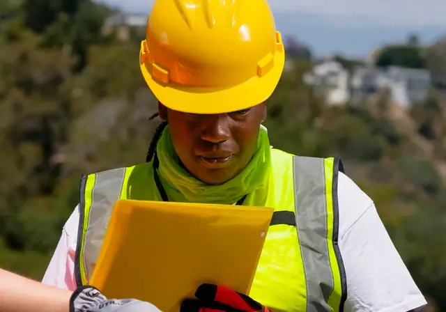 Engineer in PPE checking a plan on a tablet