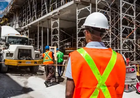Supervisor in a hi-vis vest and white hard hat on a busy site