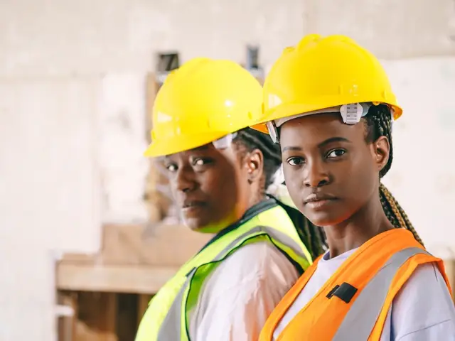 Two technicians in yellow hard hats and hi-vis vests