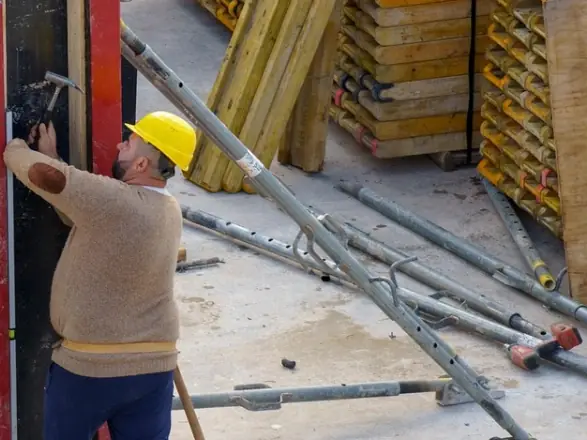 Worker setting a steel formwork panel by hand