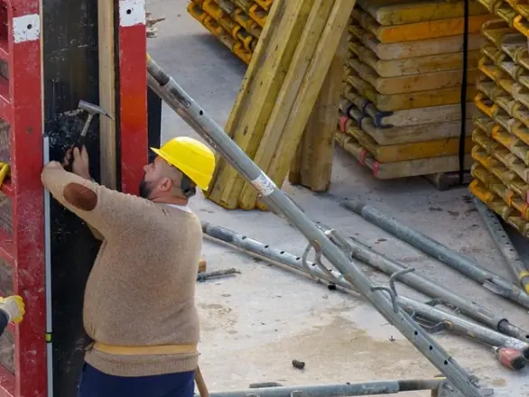 Workers fixing a steel formwork panel on site