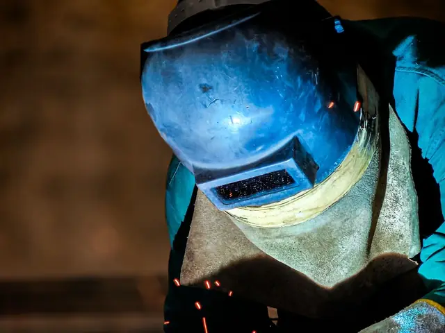 Welder working behind a protective welding helmet