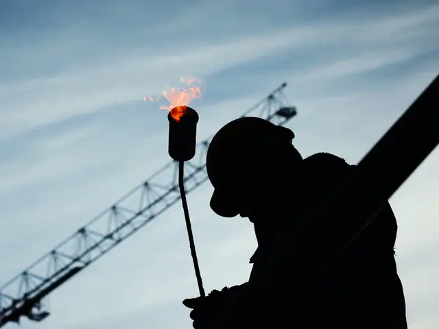 Worker silhouetted with a lit cutting torch