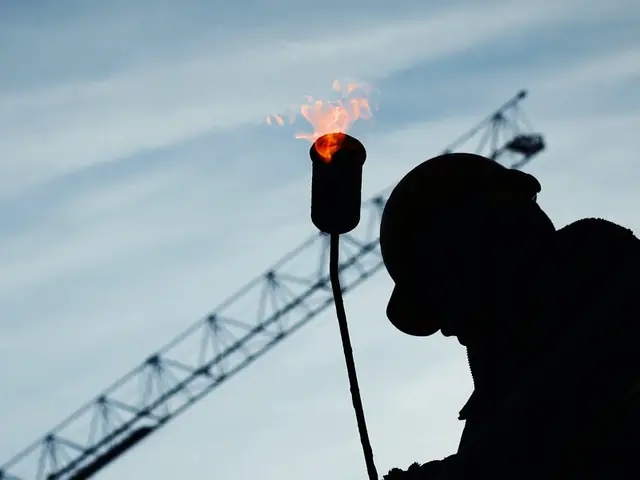 Silhouette of a worker holding a lit gas torch